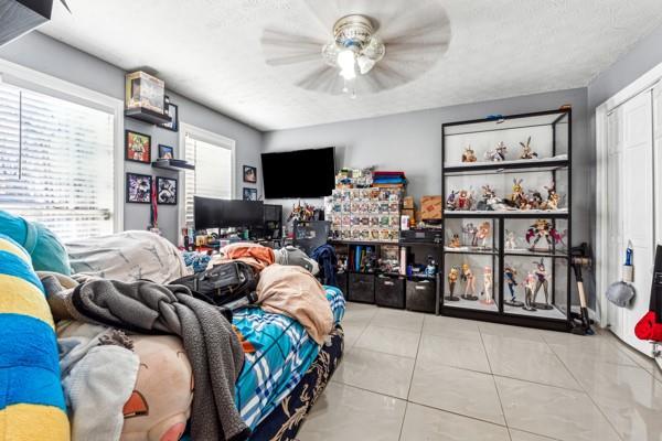 tiled bedroom with ceiling fan, a closet, and a textured ceiling