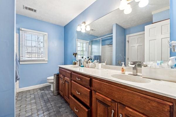 bathroom with vanity, a shower with door, and toilet