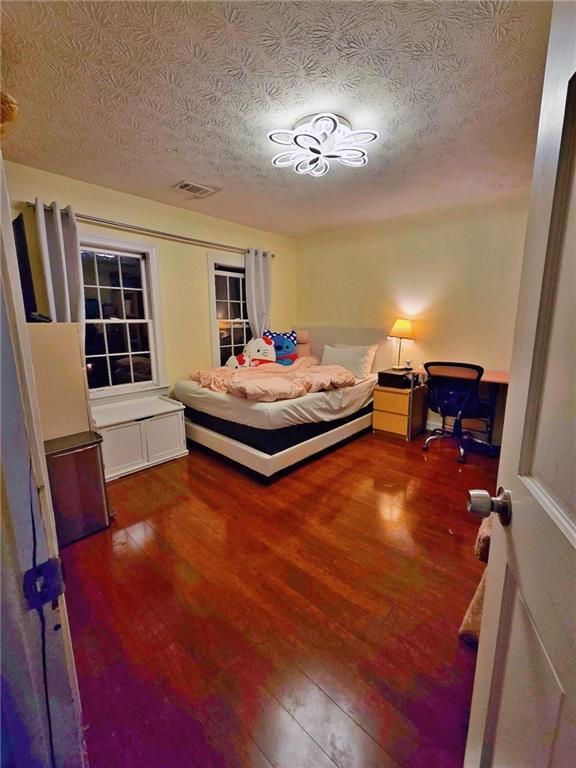 bedroom with a textured ceiling and dark hardwood / wood-style flooring