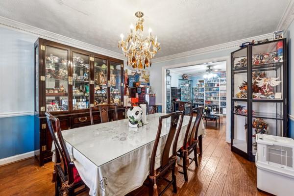 dining room with crown molding, wood-type flooring, and a chandelier