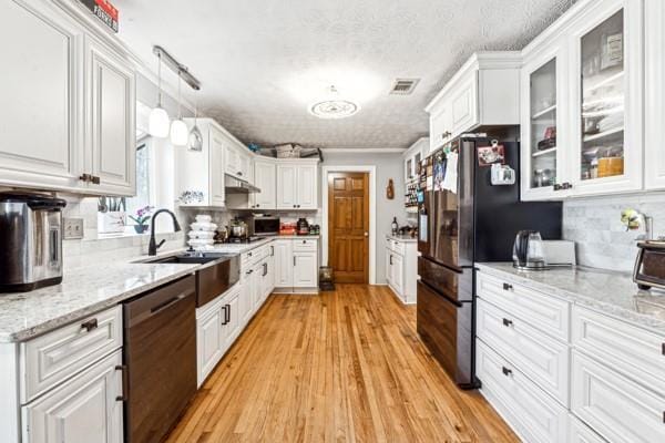 kitchen featuring sink, stainless steel fridge, black dishwasher, pendant lighting, and white cabinets