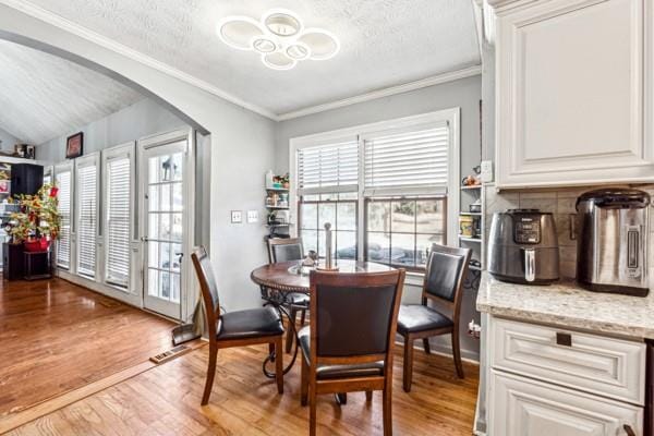 dining area featuring ornamental molding, a textured ceiling, and light hardwood / wood-style flooring