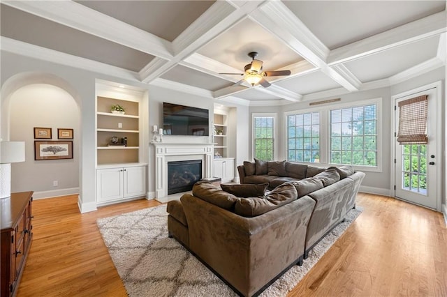 living area featuring crown molding, beam ceiling, light wood finished floors, baseboards, and a fireplace with flush hearth