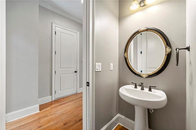 bathroom featuring baseboards, ornamental molding, and wood finished floors