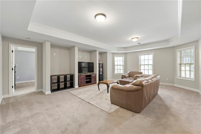 living area with a raised ceiling, baseboards, and light carpet