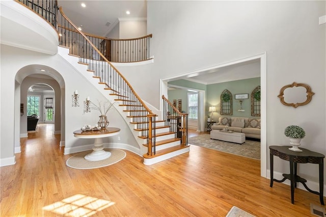 entryway featuring arched walkways, wood finished floors, a healthy amount of sunlight, and stairway
