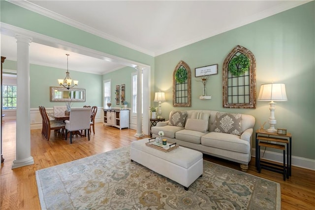 living room with crown molding, decorative columns, wood finished floors, and a wealth of natural light