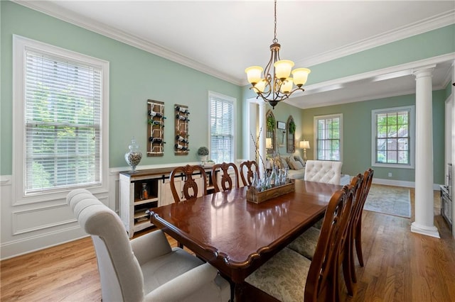 dining room with ornate columns, ornamental molding, wood finished floors, and a healthy amount of sunlight
