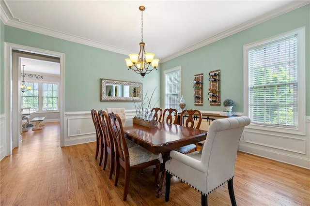 dining room with a decorative wall, a chandelier, ornamental molding, and light wood-type flooring