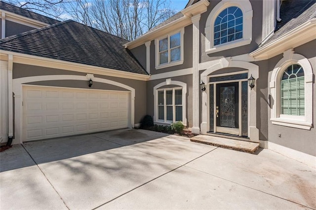 doorway to property featuring concrete driveway, a garage, and stucco siding