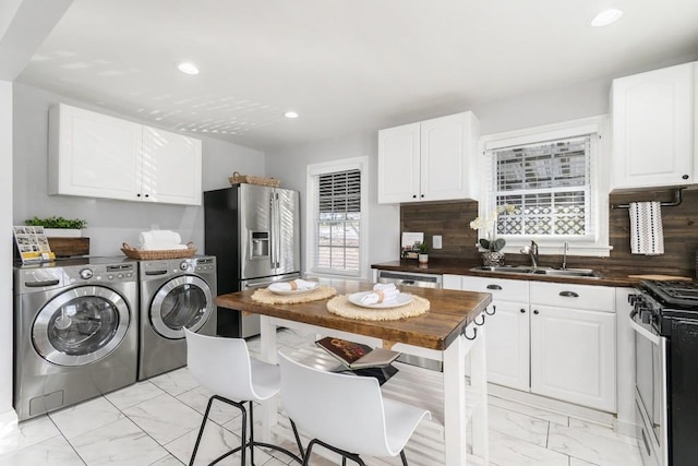 kitchen with white cabinetry, stainless steel appliances, decorative backsplash, sink, and washer and clothes dryer