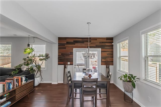 dining area with wooden walls, plenty of natural light, baseboards, and dark wood-style flooring