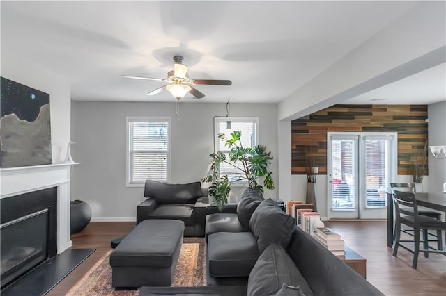 living room with ceiling fan, baseboards, a fireplace with raised hearth, and wood finished floors