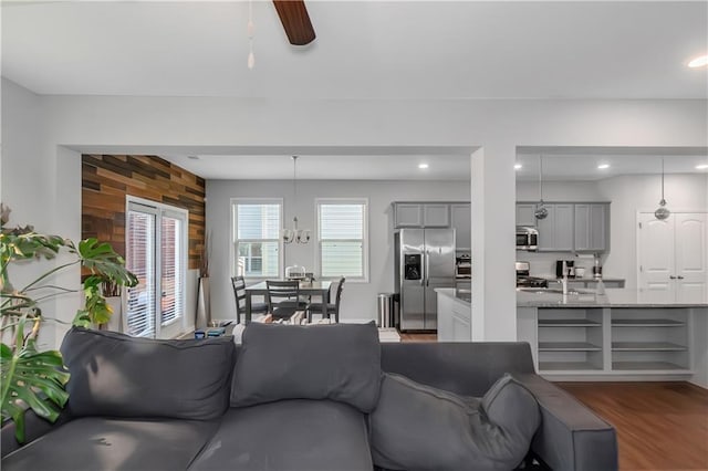 living room with a ceiling fan, recessed lighting, dark wood-style floors, and wood walls