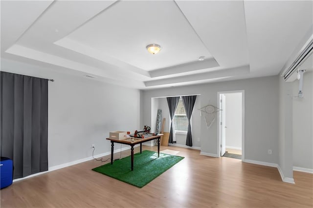 office with a tray ceiling, baseboards, and wood finished floors