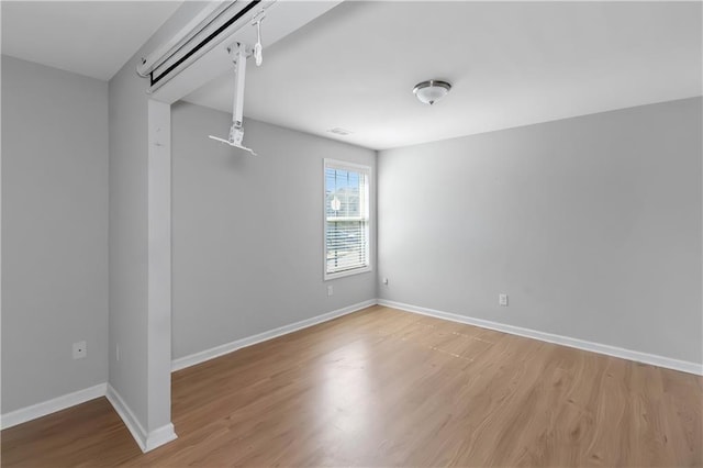 unfurnished room featuring visible vents, wood finished floors, and baseboards