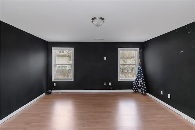 spare room with wood finished floors, visible vents, and a wealth of natural light