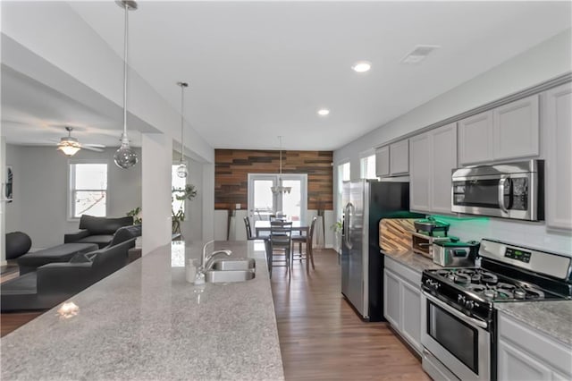 kitchen featuring plenty of natural light, appliances with stainless steel finishes, light stone countertops, and a sink