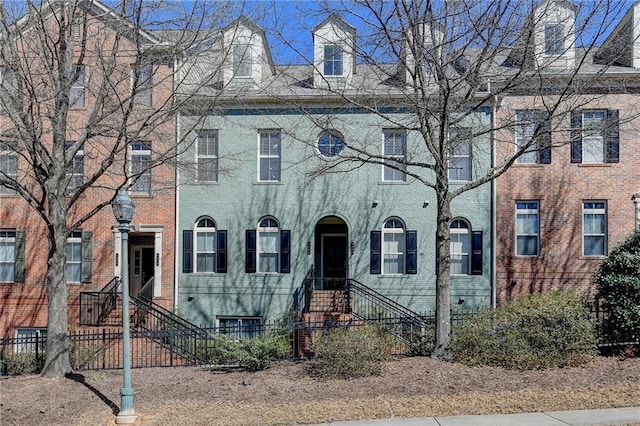 multi unit property featuring a fenced front yard and brick siding