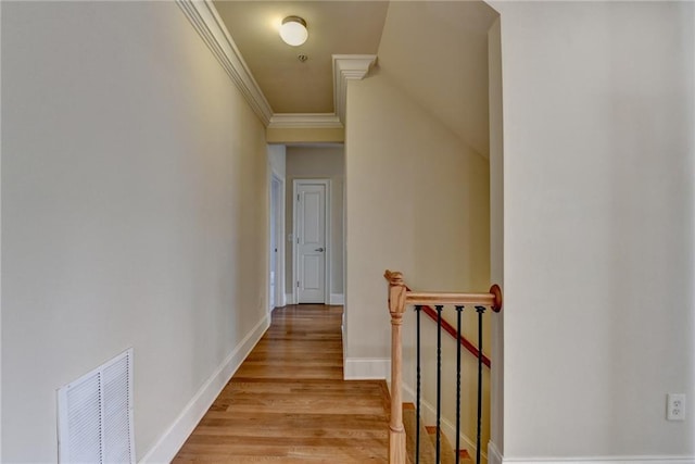 hall featuring an upstairs landing, baseboards, light wood-style floors, visible vents, and crown molding