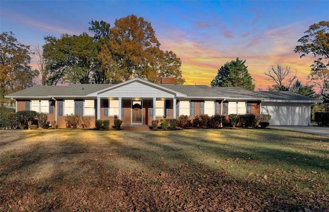 ranch-style house featuring a yard, driveway, and an attached garage