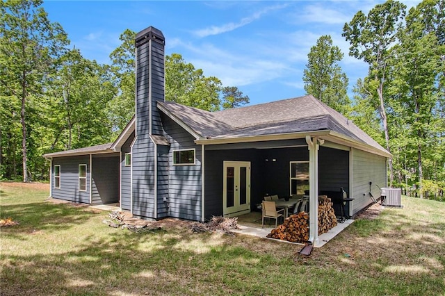 back of property featuring a yard, central AC unit, a chimney, french doors, and a patio area