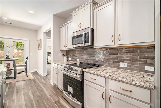kitchen with stainless steel appliances, light wood finished floors, baseboards, tasteful backsplash, and light stone counters
