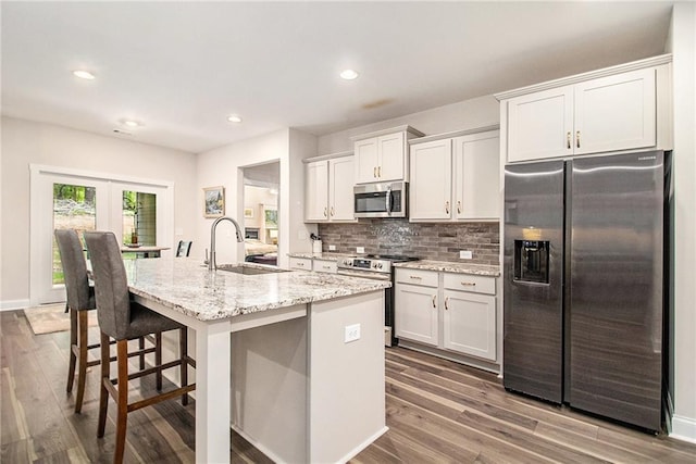 kitchen with appliances with stainless steel finishes, a sink, an island with sink, dark wood-type flooring, and recessed lighting
