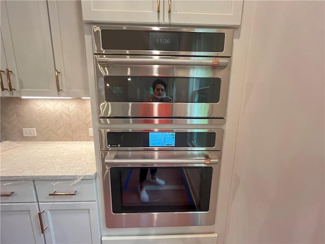 1005 Liberty Springs Dr, Woodstock, GA 30188 - kitchen with stainless steel double oven, light countertops, backsplash, and white cabinetry