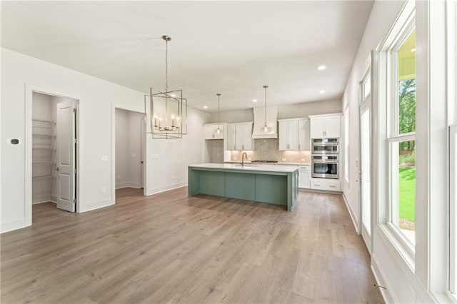 1005 Liberty Springs Dr, Woodstock, GA 30188 - kitchen with double oven, a chandelier, white cabinets, backsplash, and light wood-style floors