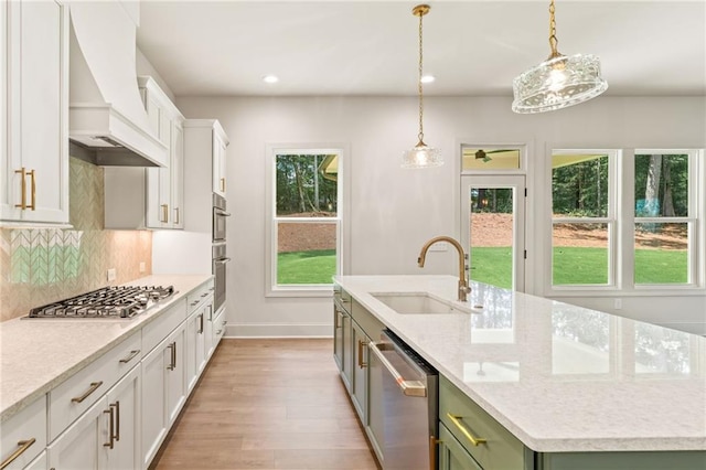 1005 Liberty Springs Dr, Woodstock, GA 30188 - kitchen featuring custom range hood, appliances with stainless steel finishes, a kitchen island with sink, light wood-style floors, and tasteful backsplash