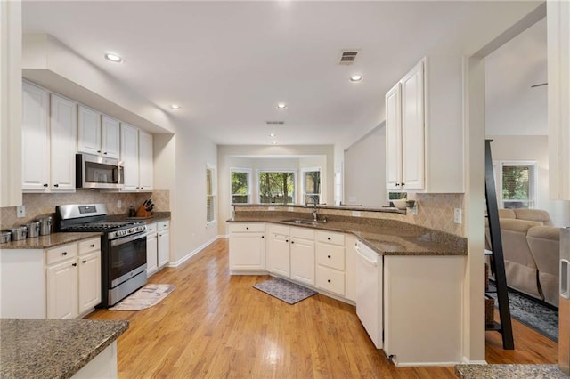 2740 Greymont Ct, Cumming, GA 30041 - kitchen with stainless steel appliances, backsplash, dark stone countertops, white cabinets, and recessed lighting