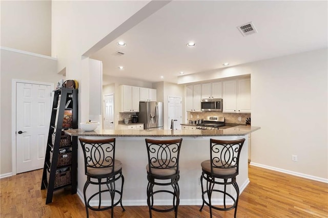 2740 Greymont Ct, Cumming, GA 30041 - kitchen featuring stainless steel appliances, backsplash, a breakfast bar, dark stone counters, and white cabinetry
