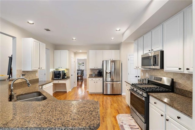 2740 Greymont Ct, Cumming, GA 30041 - kitchen with appliances with stainless steel finishes, dark stone countertops, a peninsula, light wood-style flooring, and recessed lighting
