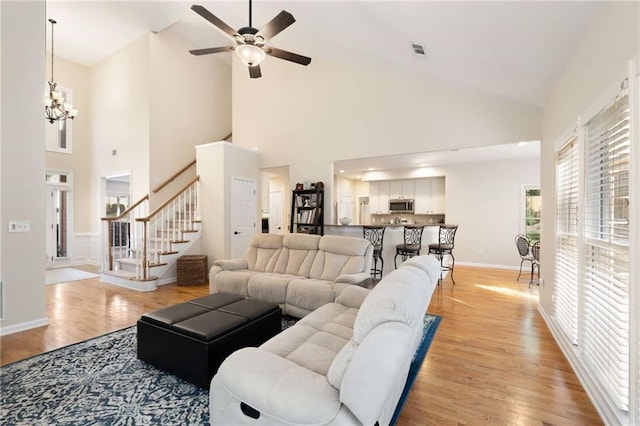 2740 Greymont Ct, Cumming, GA 30041 - living area with light wood-style flooring, stairs, high vaulted ceiling, a ceiling fan, and a chandelier