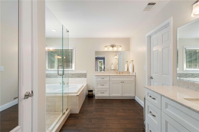 2740 Greymont Ct, Cumming, GA 30041 - bathroom featuring two vanities, a garden tub, a shower stall, and wood finished floors