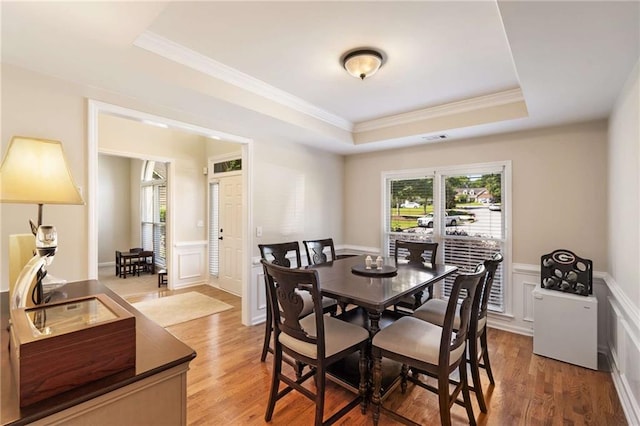 2740 Greymont Ct, Cumming, GA 30041 - dining area featuring a raised ceiling, ornamental molding, light wood-style floors, wainscoting, and a decorative wall