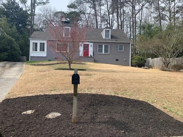 view of front of home with crawl space, fence, and a front lawn