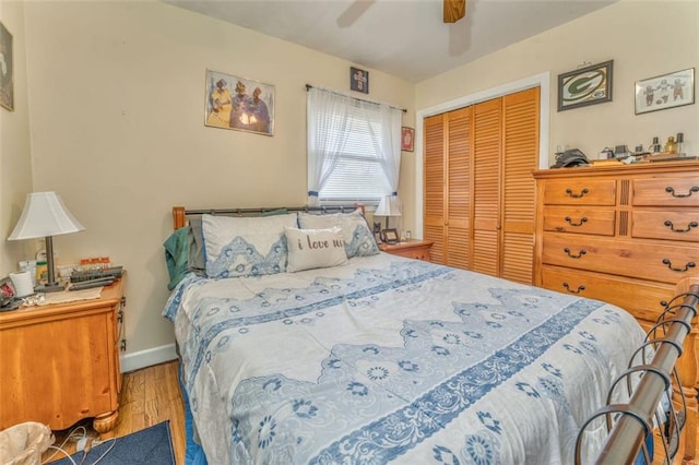 bedroom with a closet, wood finished floors, a ceiling fan, and baseboards