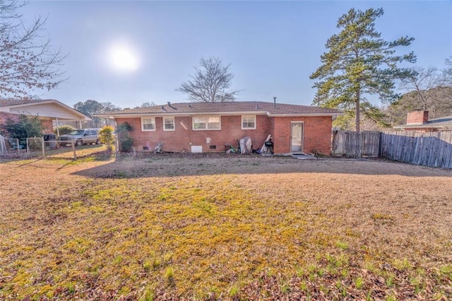 rear view of property featuring brick siding, crawl space, fence, and a lawn