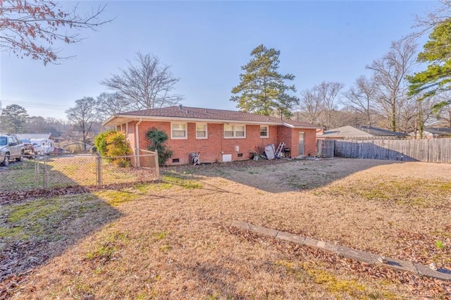 back of house with crawl space, fence, and brick siding