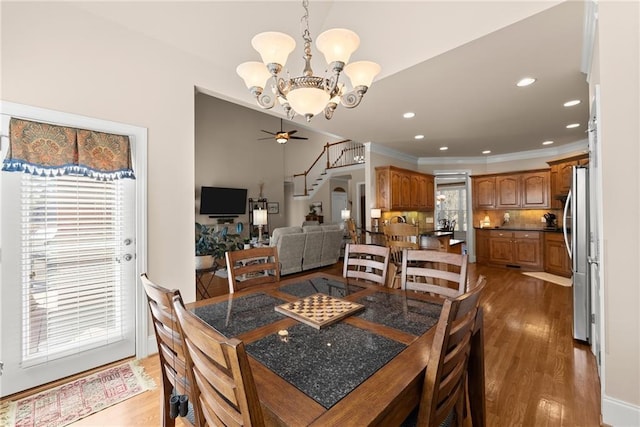 dining area with wood-type flooring, a healthy amount of sunlight, and ceiling fan with notable chandelier