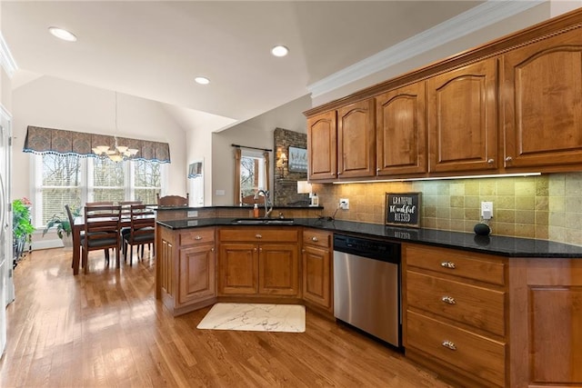 kitchen with hanging light fixtures, sink, stainless steel dishwasher, and backsplash