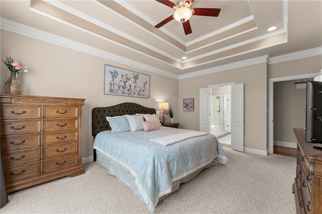 carpeted bedroom with ceiling fan, ornamental molding, a tray ceiling, and ensuite bathroom