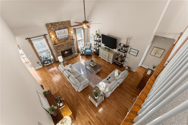 living room featuring ceiling fan, high vaulted ceiling, a fireplace, and hardwood / wood-style floors