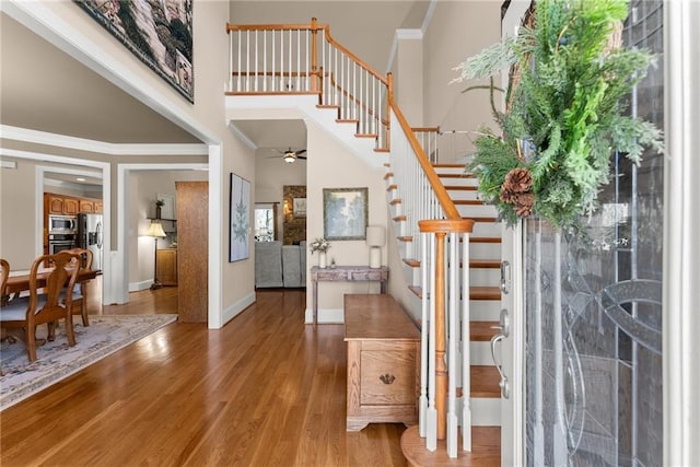 entrance foyer featuring hardwood / wood-style flooring, crown molding, a high ceiling, and ceiling fan