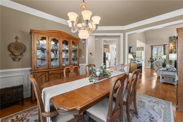 dining space featuring hardwood / wood-style flooring, ornamental molding, and an inviting chandelier