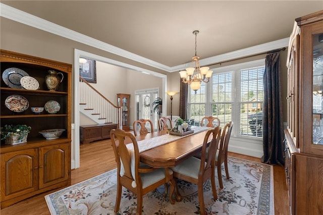 dining room featuring a notable chandelier, light hardwood / wood-style flooring, and ornamental molding