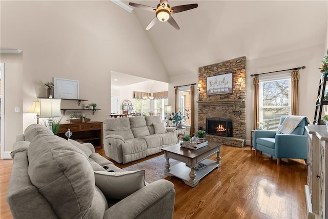 living room featuring ceiling fan, a stone fireplace, hardwood / wood-style floors, and high vaulted ceiling