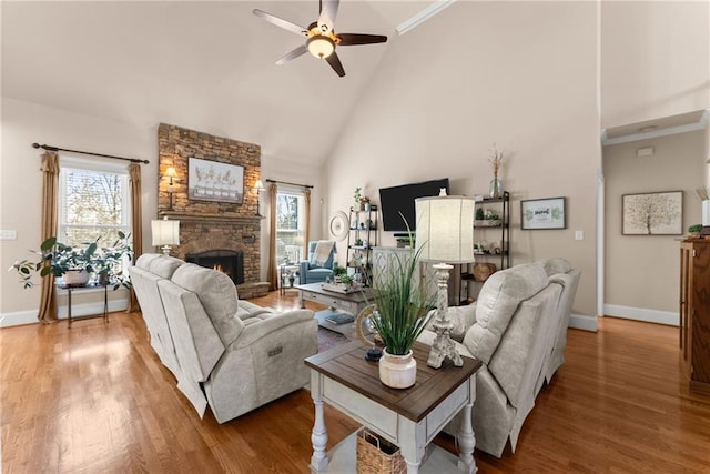 living room featuring hardwood / wood-style flooring, ceiling fan, high vaulted ceiling, and a fireplace